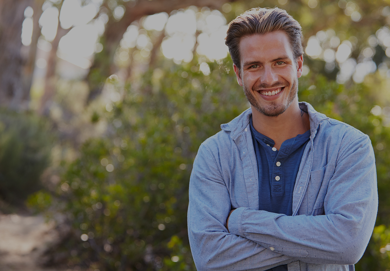 A man in casual attire standing outside smiling at the camera. 