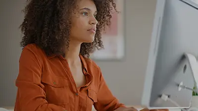 Woman dressed in casual attire using desktop computer.
