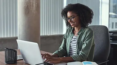 Woman in business casual attire using a laptop.
