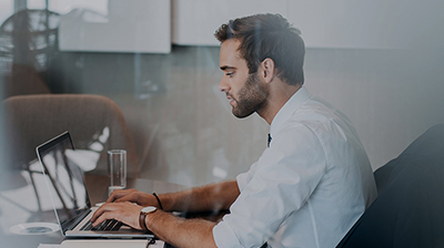 Man in business casual attire sitting and using laptop.