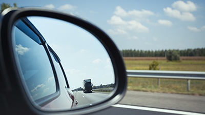 Rearview mirror displaying the large truck behind the vehicle on the road.