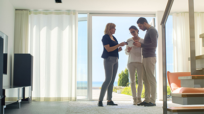 Three people dressed in casual attire interacting with a tablet in a home.