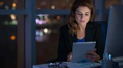 A woman using a tablet at night in the office