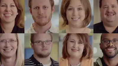 Two rows of seven people smiling and looking forward dressed in casual attire.
