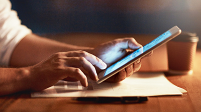 A man's hands resting on a table, holding a mobile phone