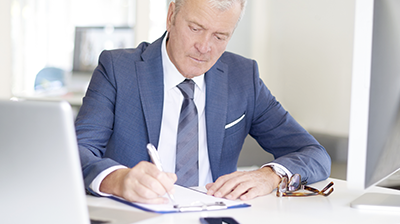 A man in a suit writing on a clipboard