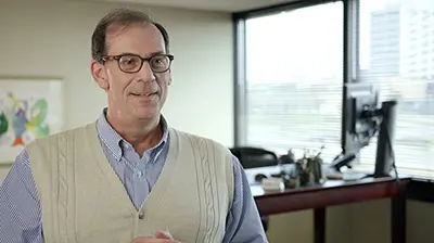 A man in a sweater vest smiling at the camera