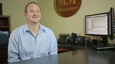 A man in a button down shirt sitting at his desk