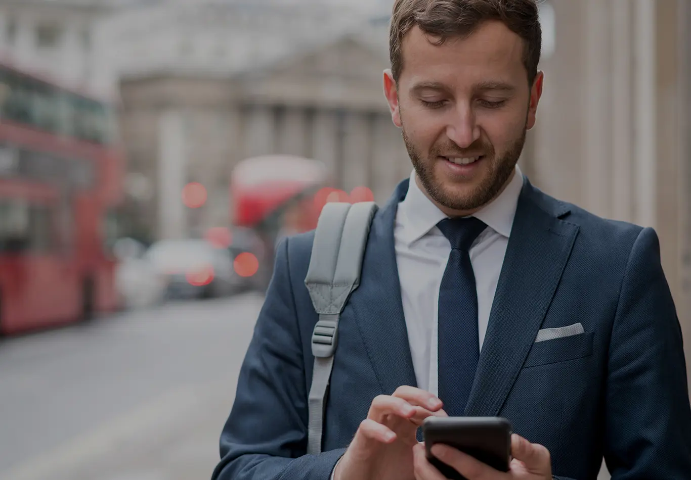 A business man in a suit is interacting with his phone on the street