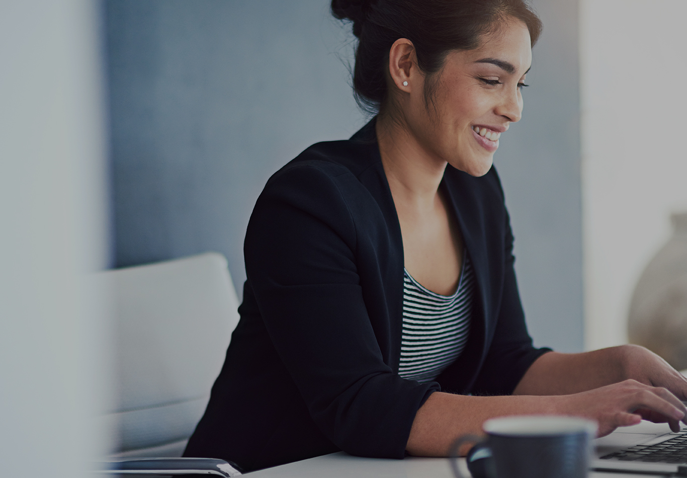 A woman with black hair is working on her laptop
