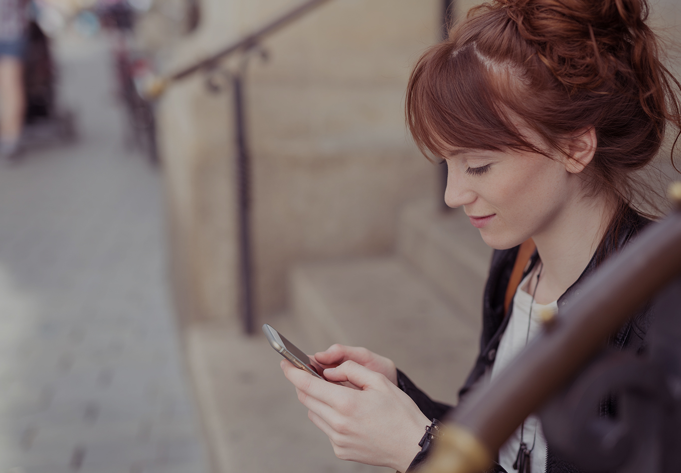 A woman is sitting on the steps looking at her phone