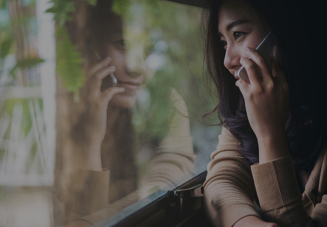 A woman on a cell phone is looking at a window