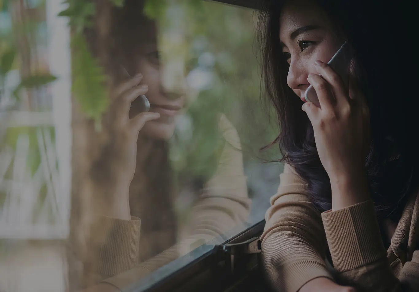A woman on a cell phone is looking at a window