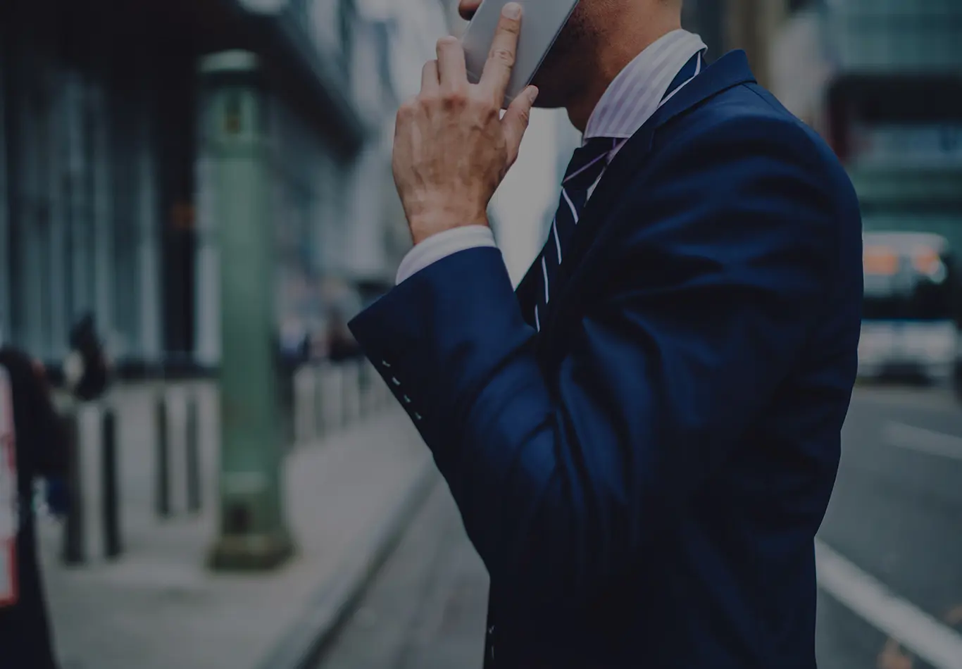 A person wearing a blue suit is talking into a cell phone