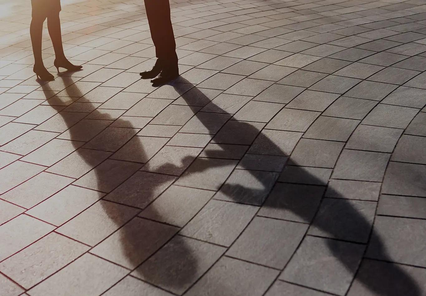 Close up of the legs and feet of a man and woman and their shadows.