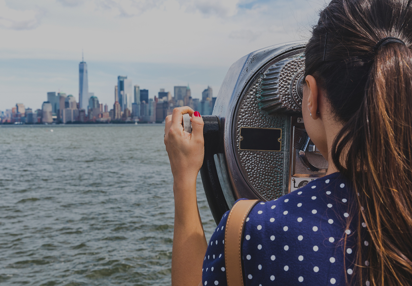 Woman looking through magnifier at a city skyline and river in front of her