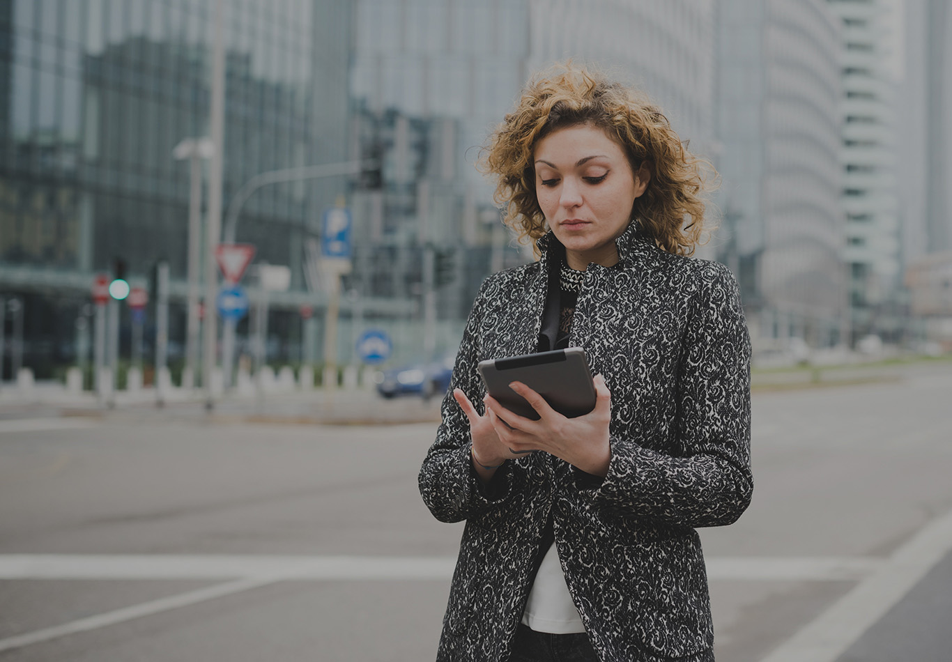 A woman is on the street looking at a tablet