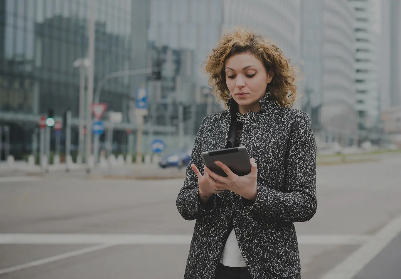 A woman is on the street looking at a tablet