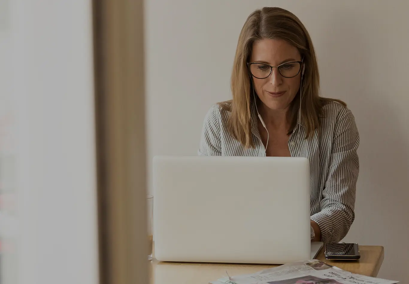 A business woman wearing headphones is looking at her computer