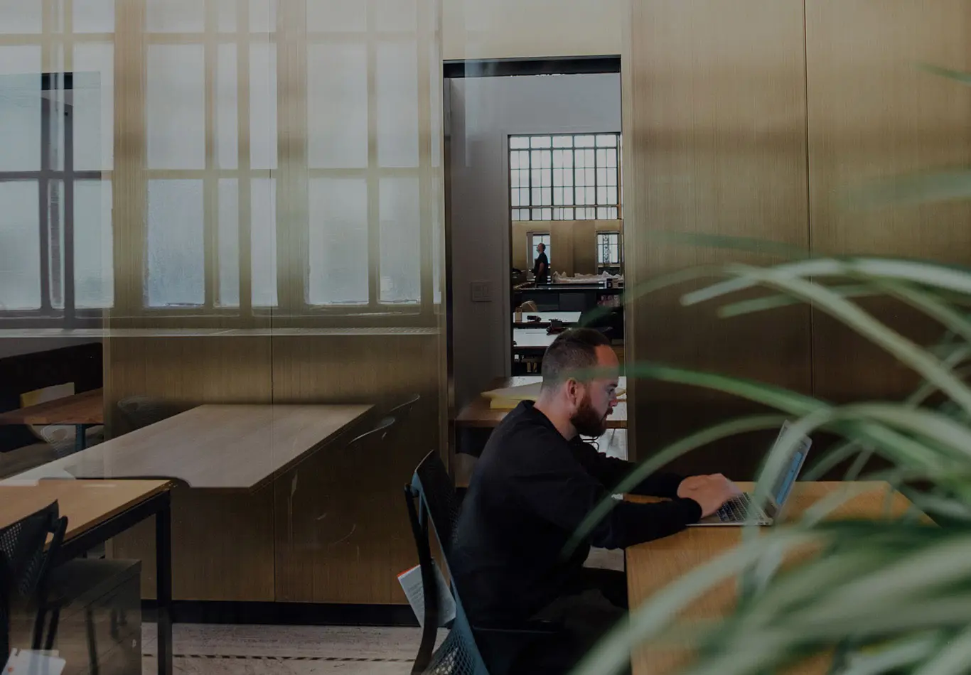 A man is sitting on at a table working on his laptop. 