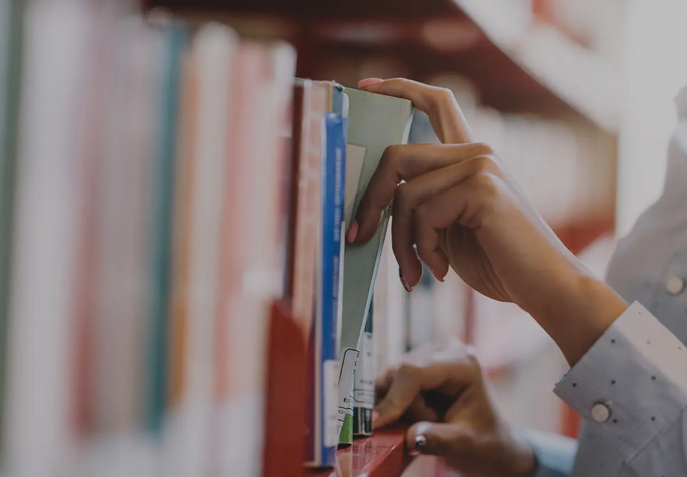 A person is taking a book off of the shelf