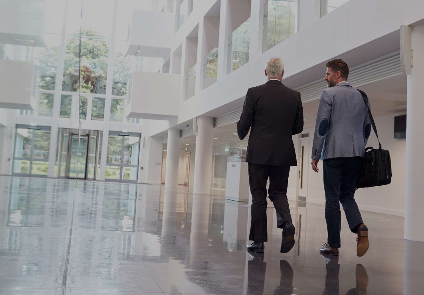 Two people are walking down an atrium side by side talking