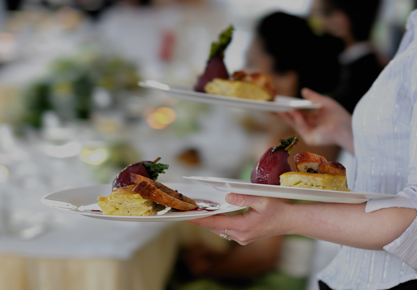 A service staff is holding three plates of food