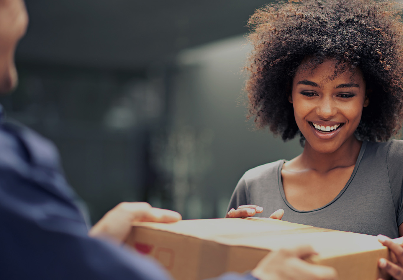 A woman with curly brown hair accepts a package