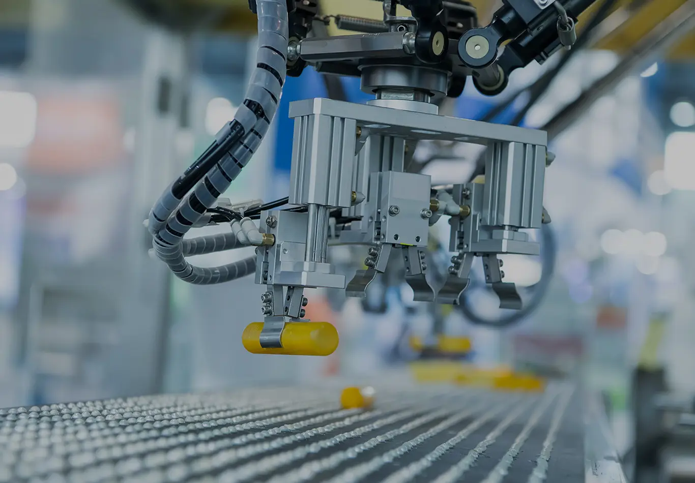 A robot on an assembly line is holding a yellow tube