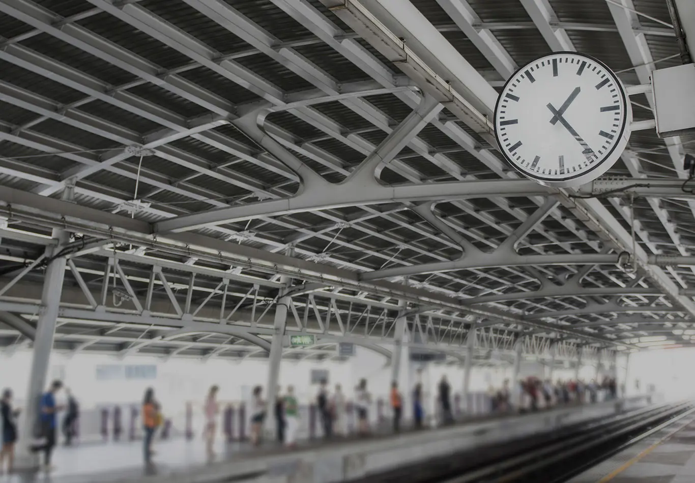 A clock in a train station is pointing to the time 1:25