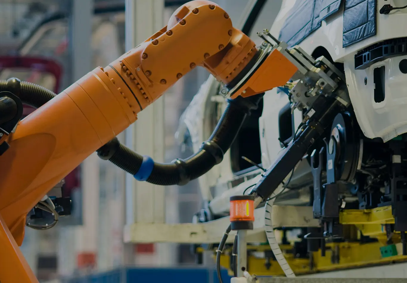 A robot arm is installing something on an automobile in an assembly line.