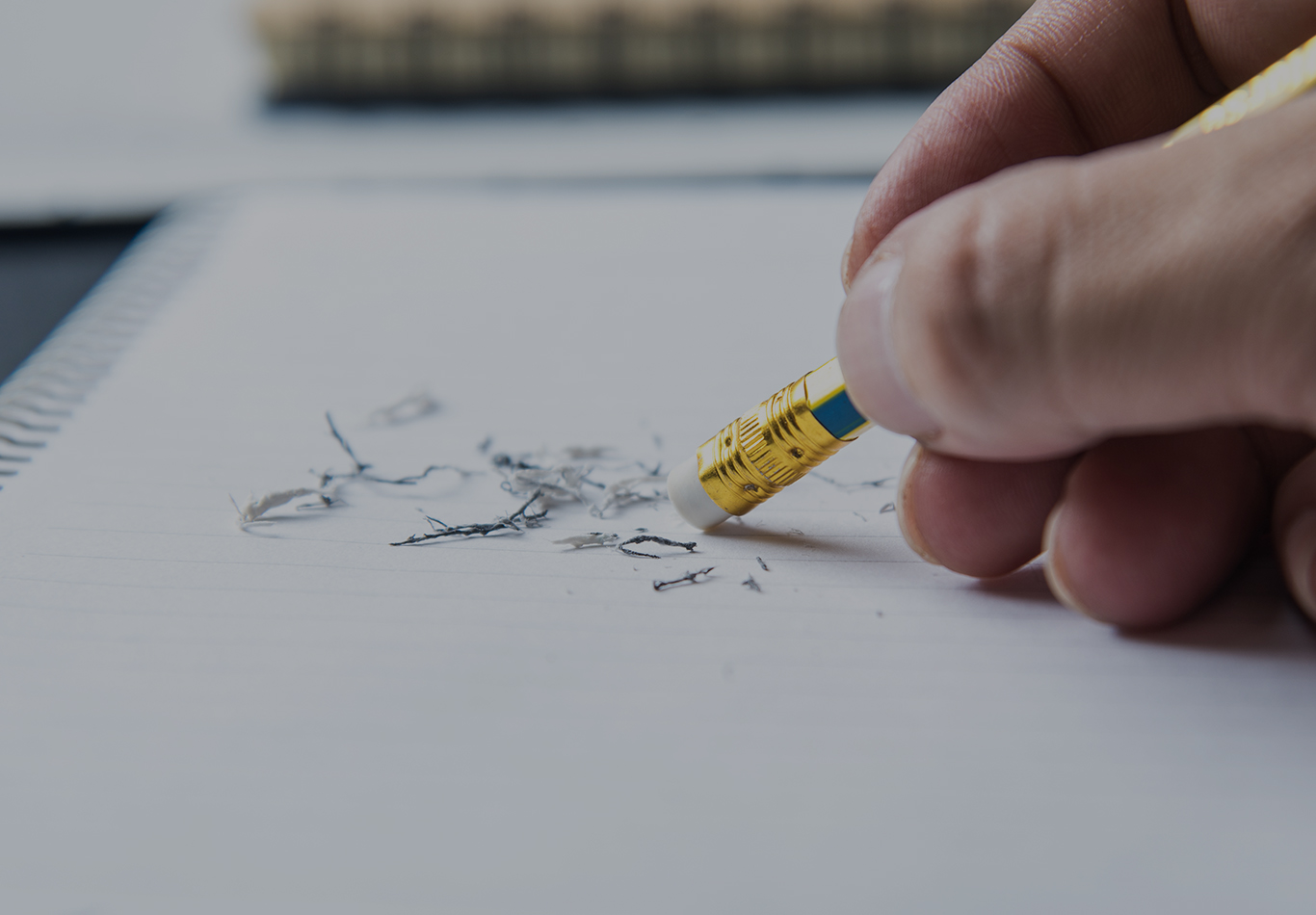 A hand holding a pencil is doing some erasing. 