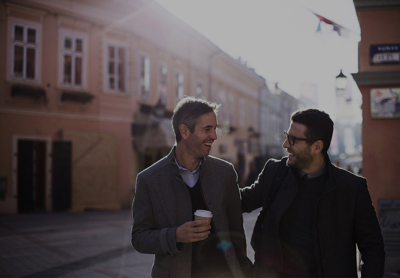 Two colleagues are walking with each other. One person is carrying a coffee cup