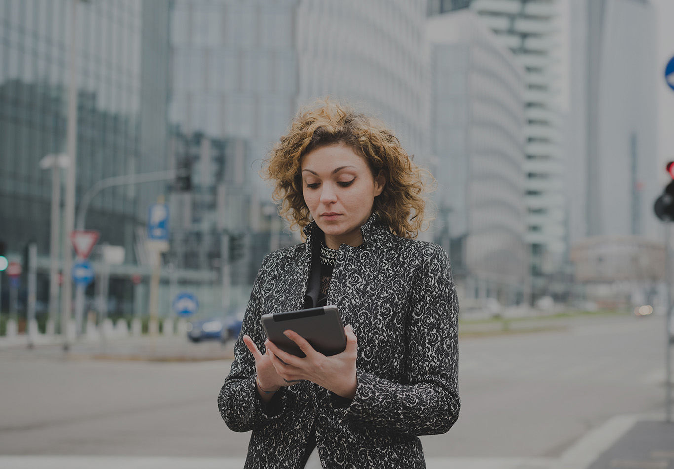 A woman is on the street looking at a tablet