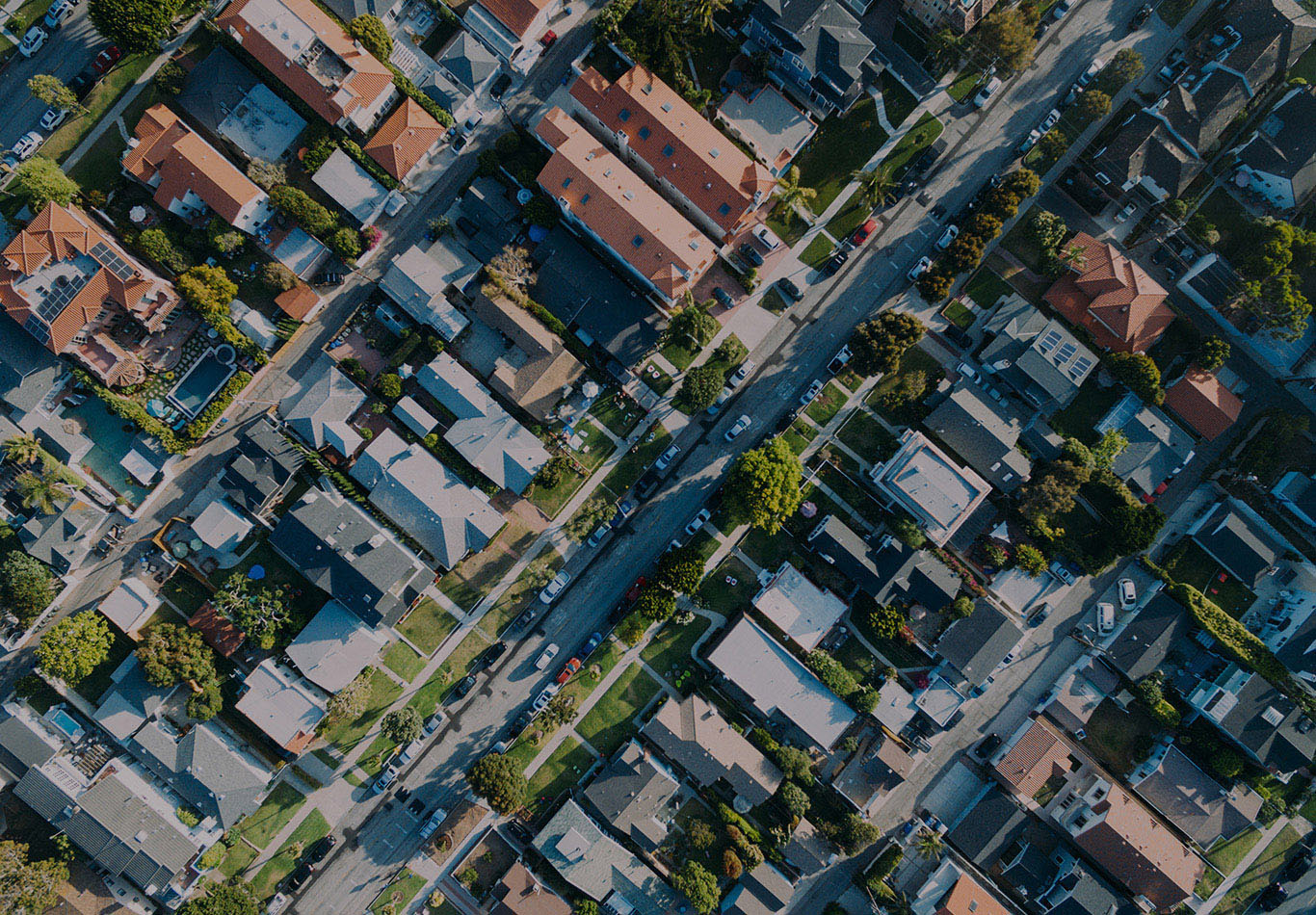 Aerial view of a neighborhood. There are a multiple cars in the street