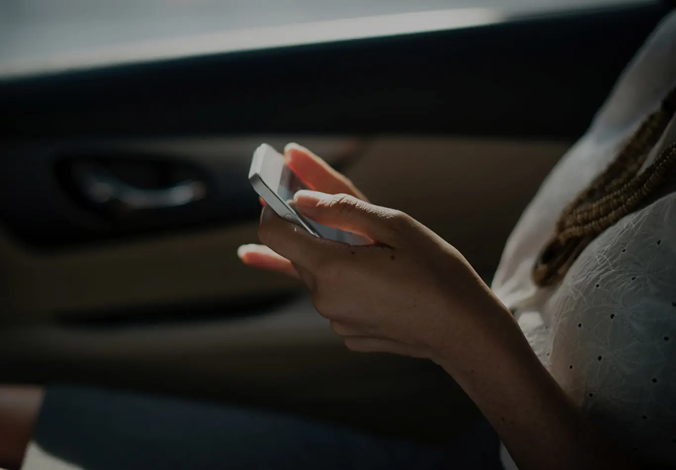 Hands are holding a phone in a car. 