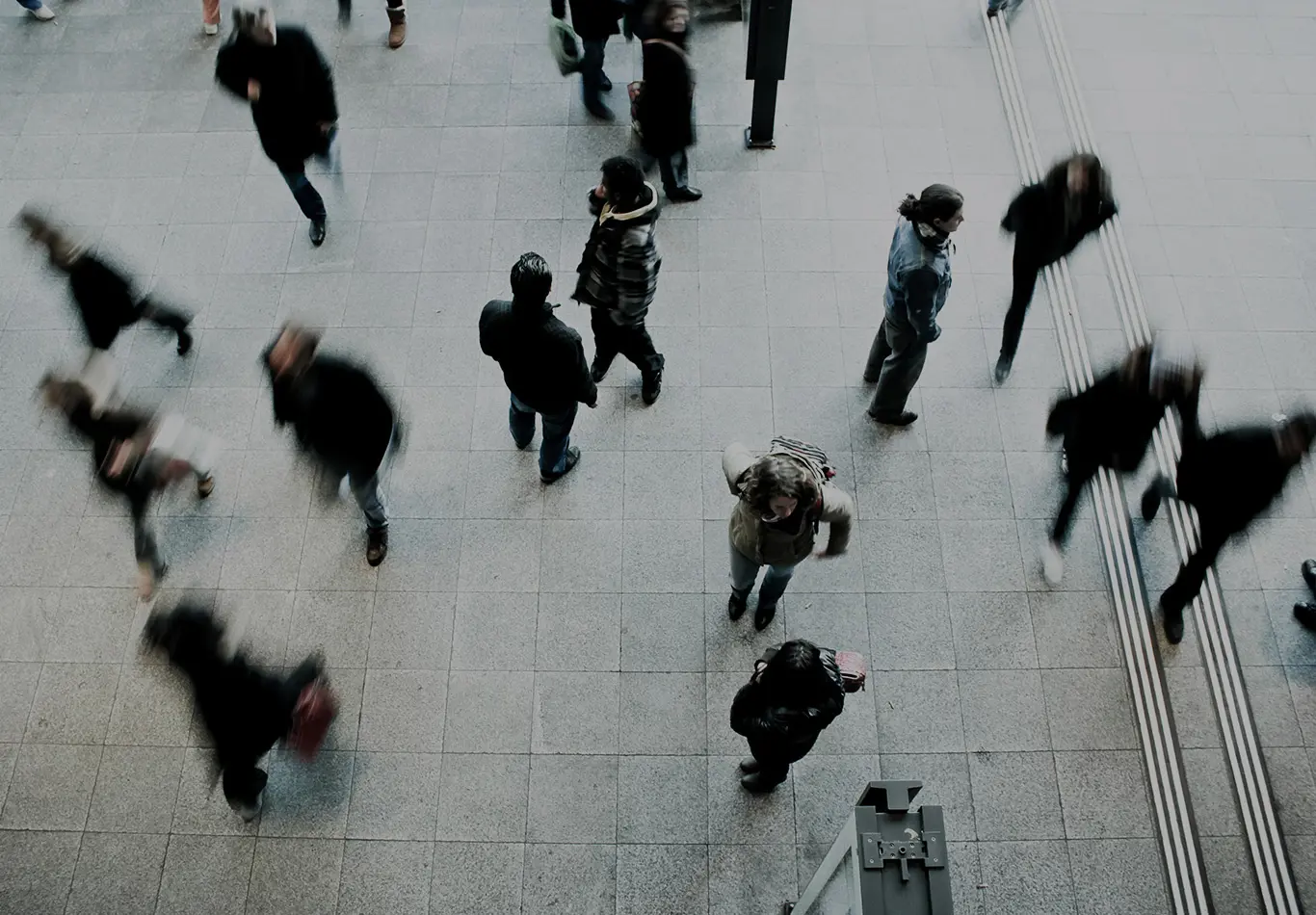 Five in-focus people are walking on a crowded floor
